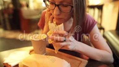 戴眼镜的饥饿女人的特写镜头正在吃一只美味的鸡肉。